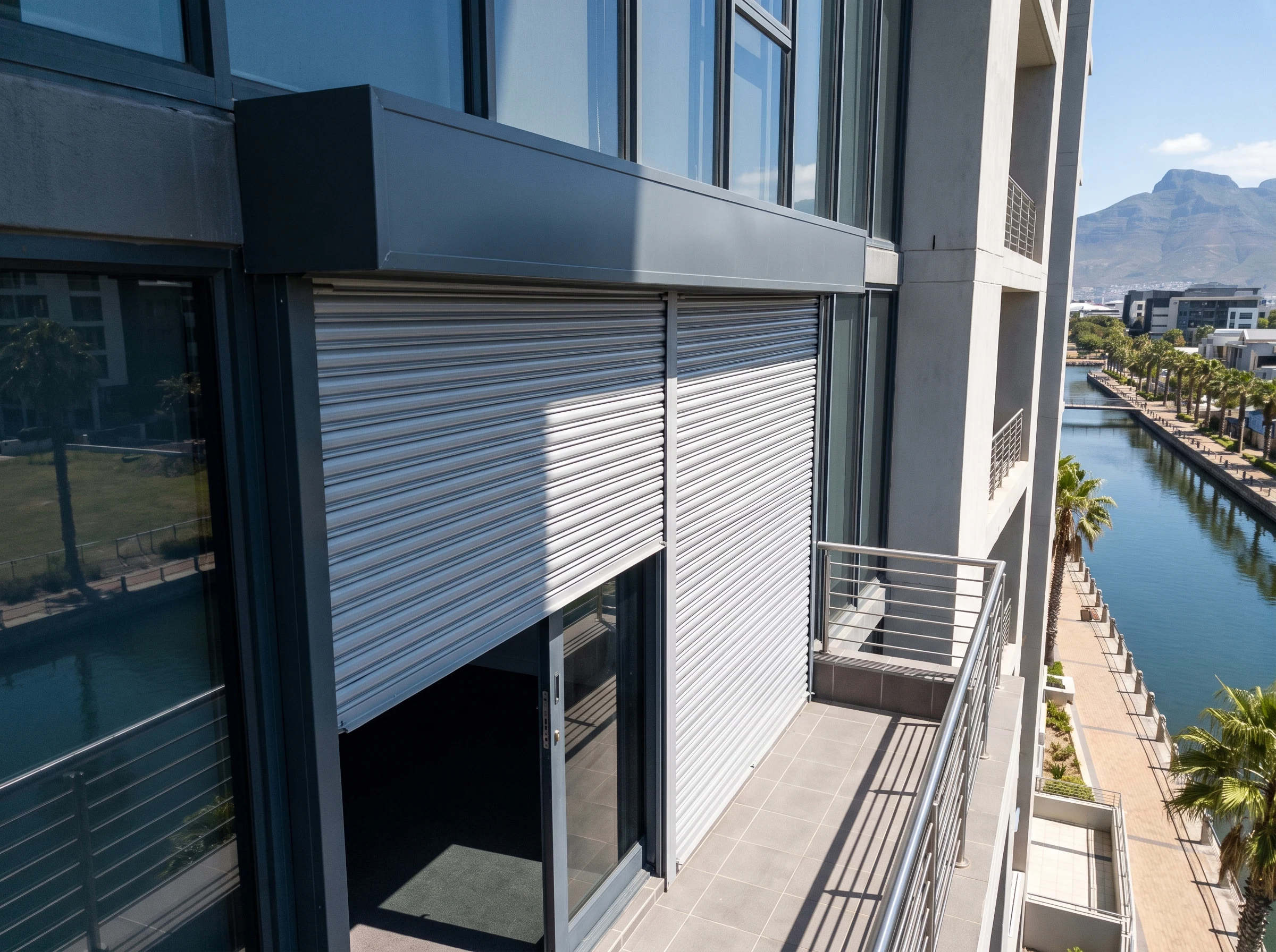 External aluminium roller shutter partly lowered from a headbox outside a Century City apartment balcony door